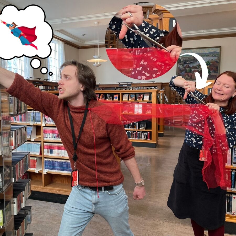 Bilde av bibliotekarene Tonje og Thorbjørn, der Thorbjørn poserer som en superhelt med rød kappe, mens Tonje klipper av heltekappen mens hun smiler med skadefryd. 