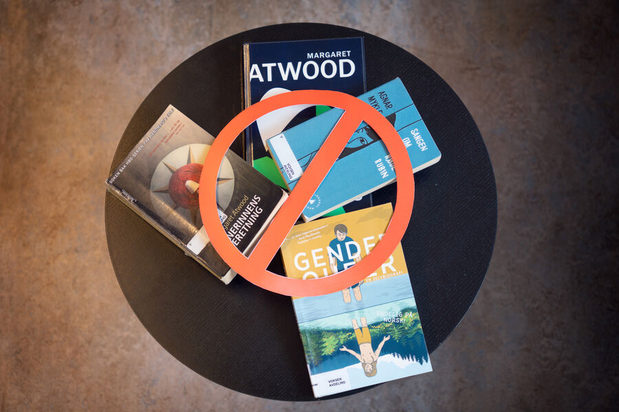 Bilde av forskjellige bøker liggende på et bord som har blitt sensurert med et forbudt skilt foran