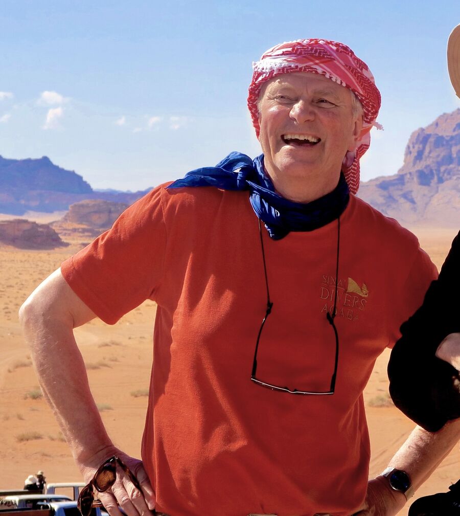 Bilde av Frode Rekve som står i rød t-skjorte og hodetørkle med en ørken i bakgrunnen