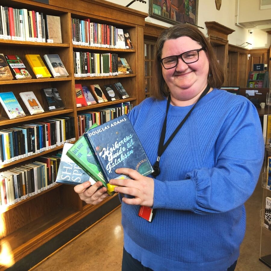 Bilde av bibliotekar Linda som holder opp bøker av Douglas Adams